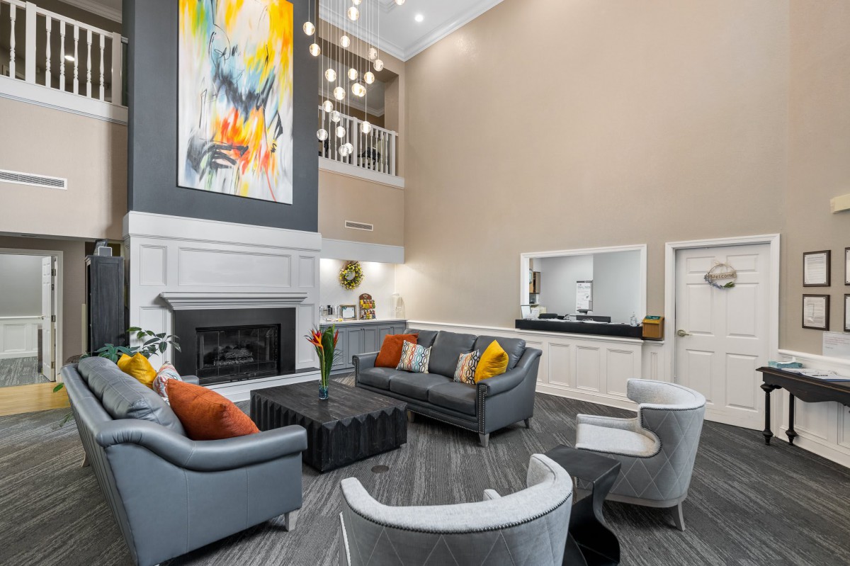 A modern living room with colorful artwork, comfortable seating, and stylish pendant lighting.