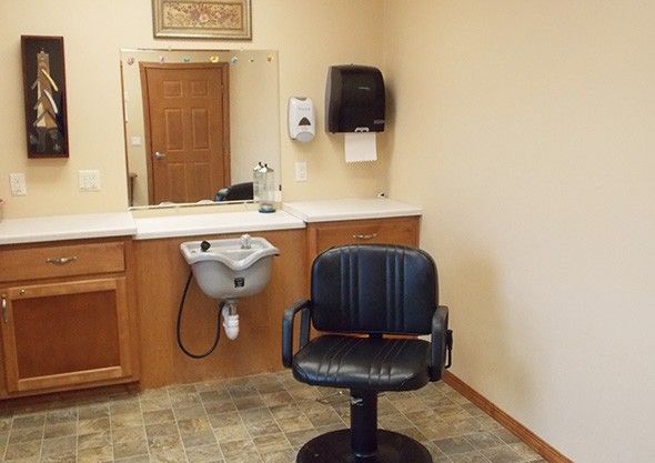 A hair salon interior featuring a barber chair, sink, and mirror.