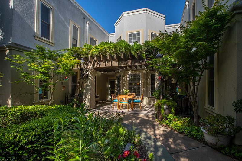 A tranquil courtyard garden with a pergola and outdoor seating surrounded by lush greenery.