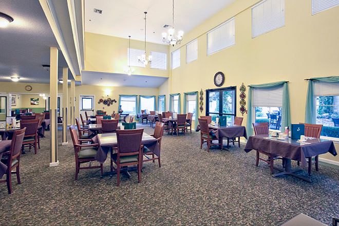 A spacious dining area with tables and chairs, featuring large windows and elegant lighting.