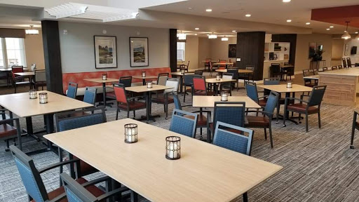 A spacious and modern dining area featuring neatly arranged tables and chairs, illuminated by soft lighting.