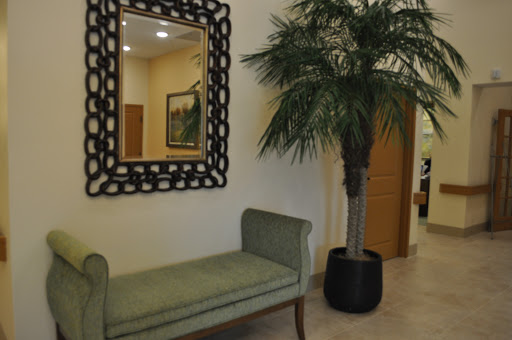 A stylish interior featuring a decorative mirror, a green bench, and a potted palm tree.