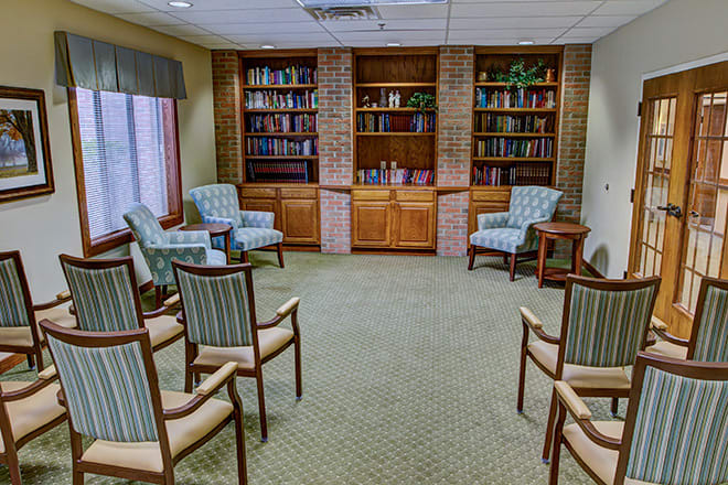 A cozy meeting room with arranged chairs and bookshelves.