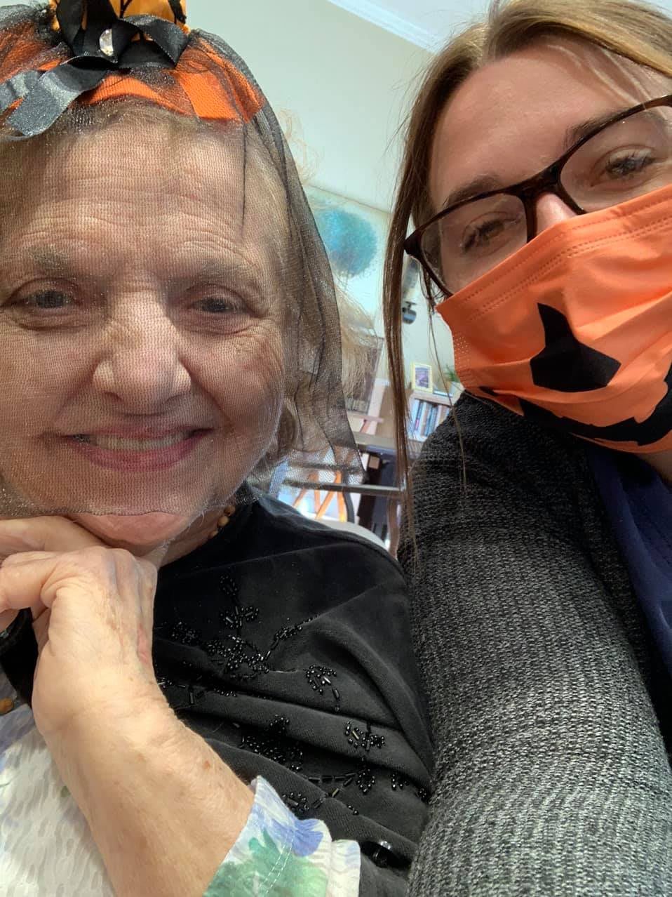A cheerful selfie of two people, one wearing a mask with a pumpkin design.