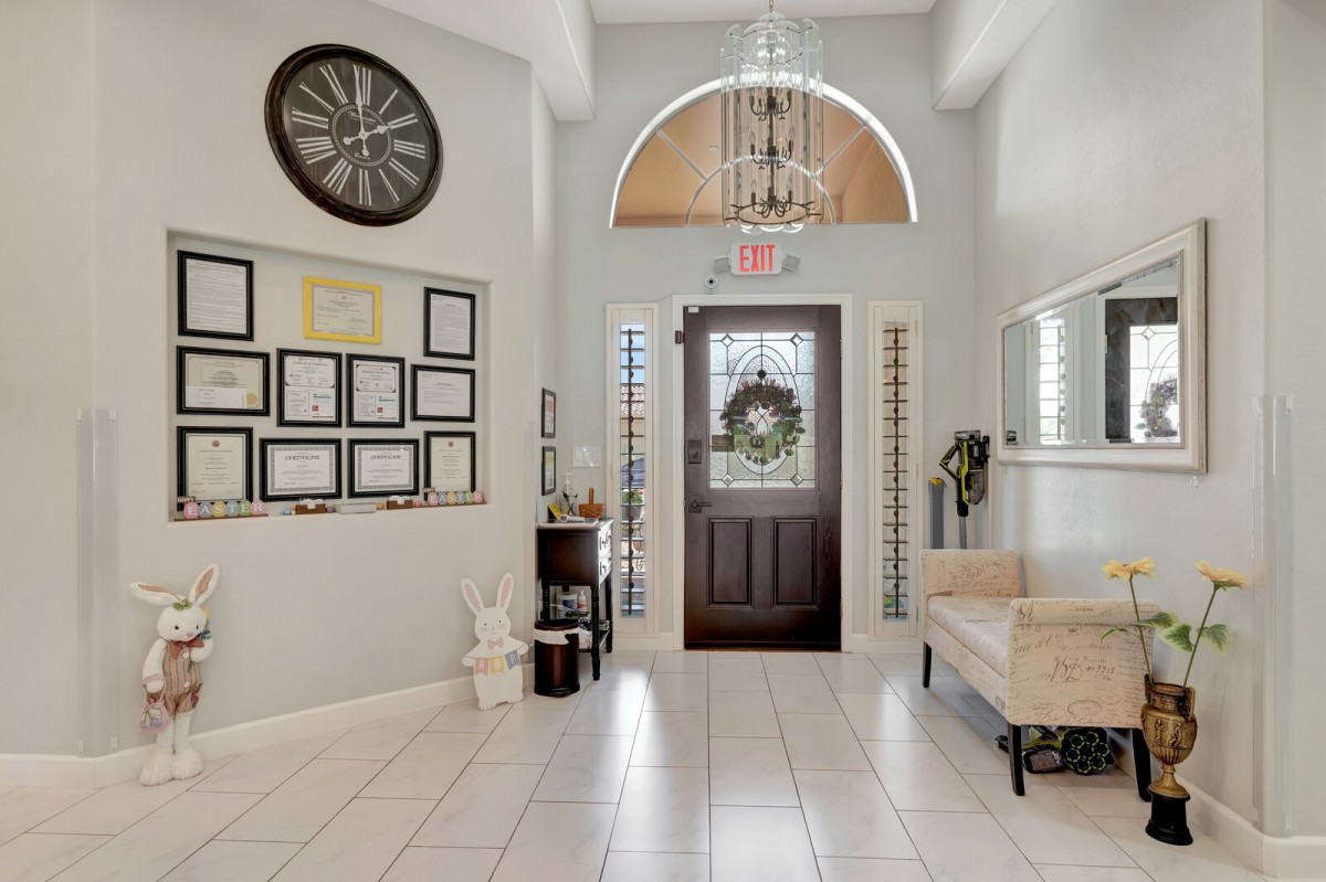 A beautifully decorated entryway with a chandelier, large clock, and picture frames adorning the walls, creating an inviting atmosphere.