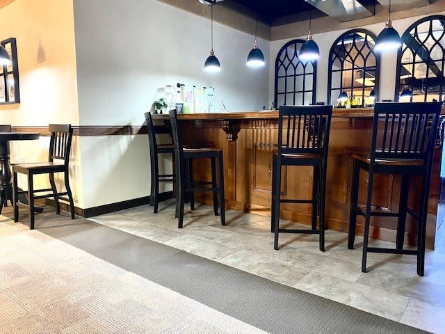 A cozy bar area with wooden high chairs and ambient lighting.