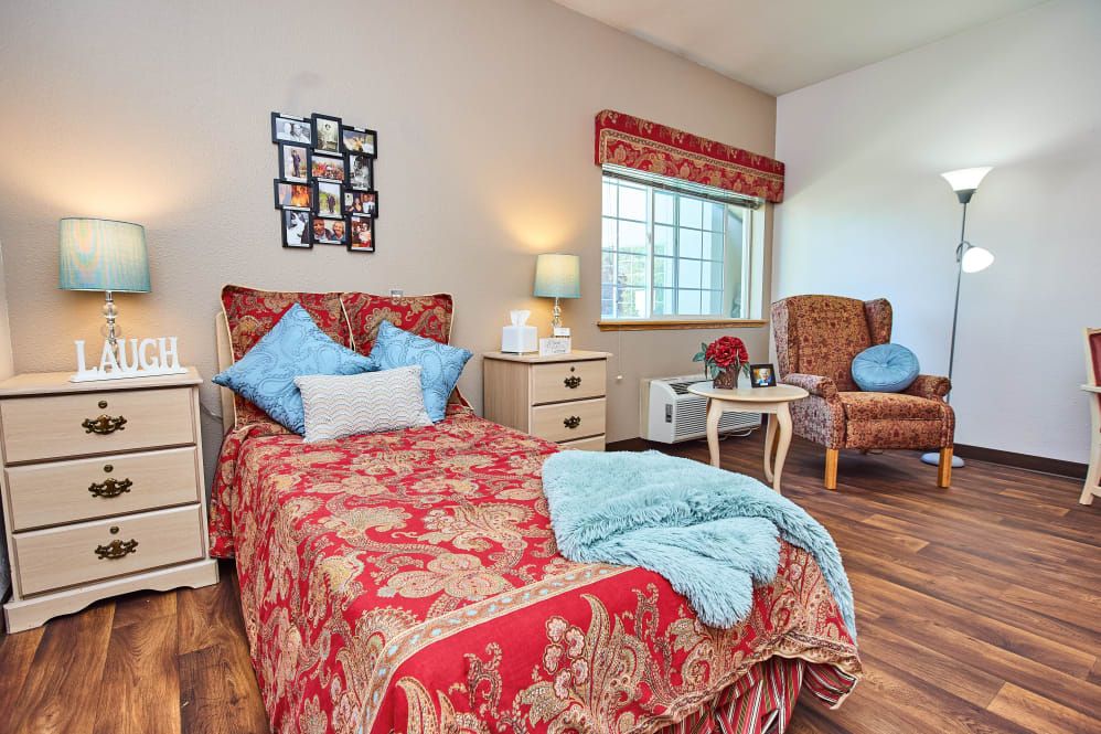A cozy bedroom with a red-patterned bedspread, light blue pillows, and warm decor accents.