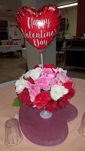 A beautiful Valentine's Day centerpiece featuring a mix of red, pink, and white flowers topped with a heart-shaped balloon.