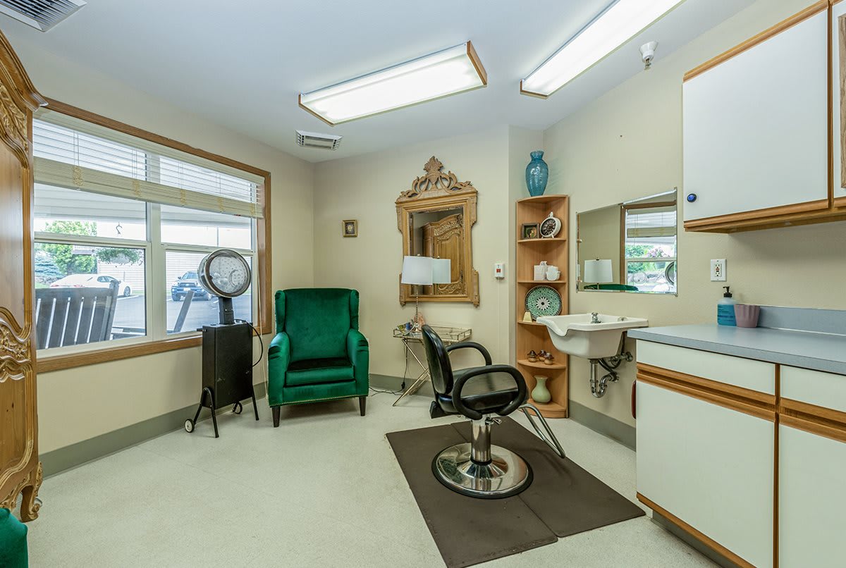 A well-lit salon interior featuring a styling chair, large mirror, and decorative elements.