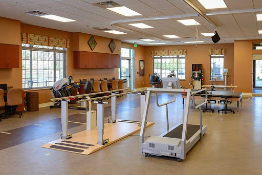 A spacious rehabilitation gym equipped with exercise machines, including a treadmill, designed for fitness and recovery.