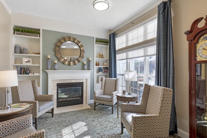 A cozy living room with a fireplace, large windows, and comfortable seating.