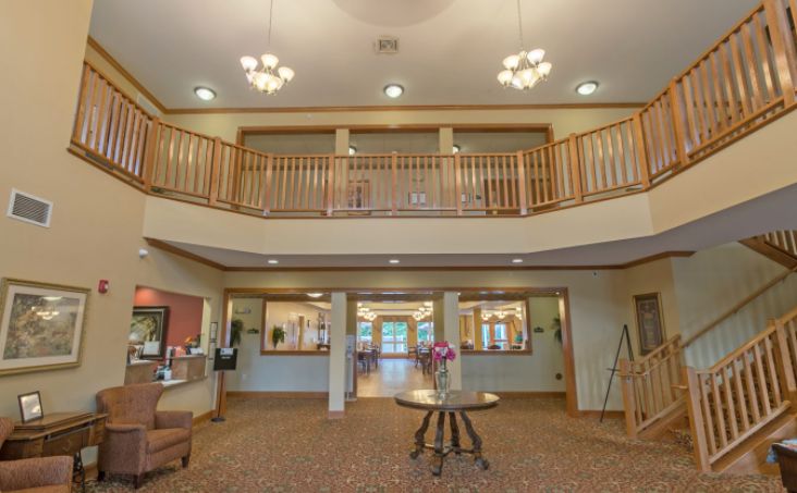 A spacious lobby with chandeliers, a wooden railing, and cozy furniture.
