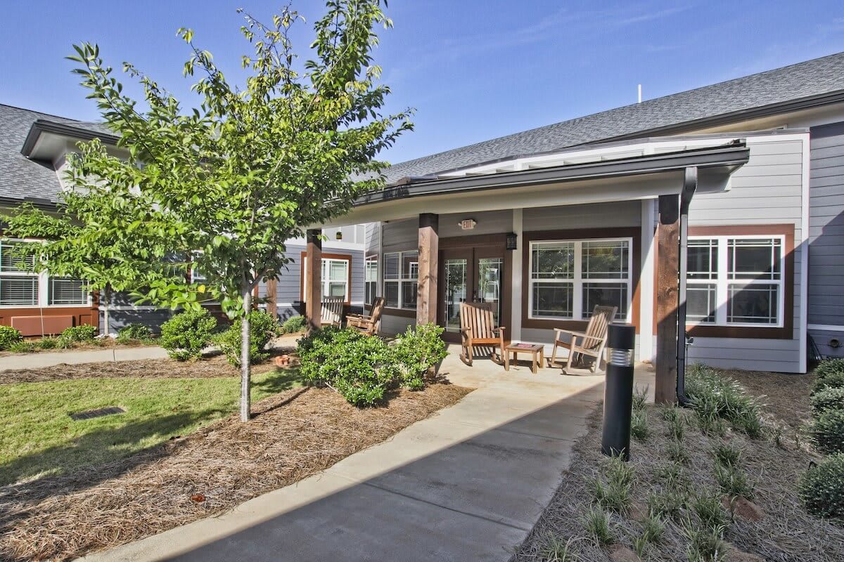 Outdoor seating area in front of a modern building with landscaped surroundings.