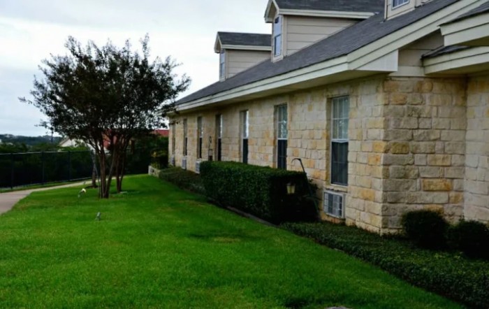 A residential house with a well-maintained lawn and stone exterior.