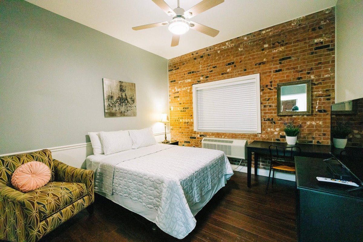 A cozy modern bedroom featuring a brick accent wall and stylish furnishings.