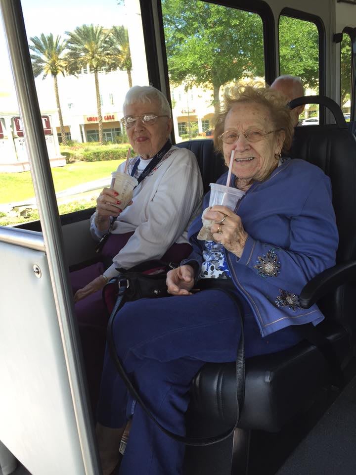 An elderly couple enjoying drinks while seated on a bus.