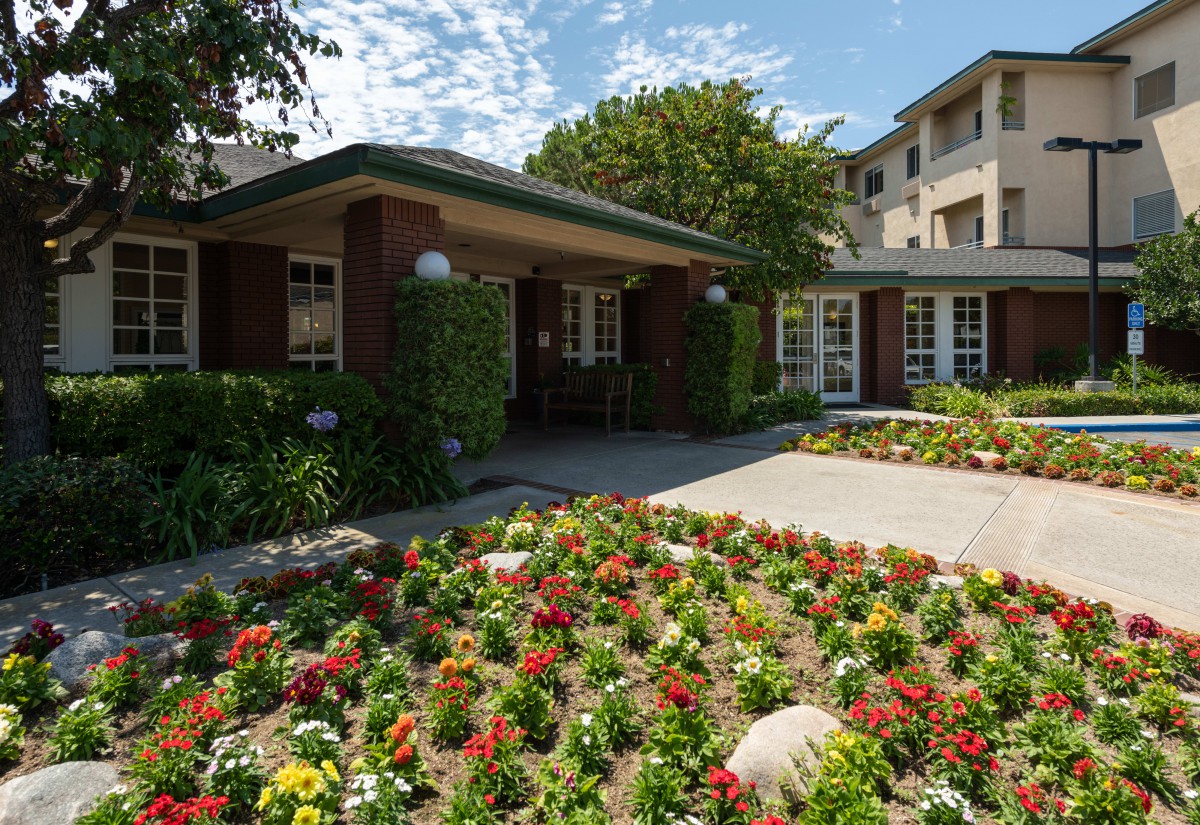 A residential building with a vibrant flower garden under a sunny sky.