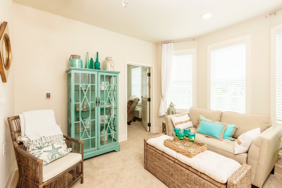 A bright living room with coastal decor featuring turquoise accents and a glass cabinet.