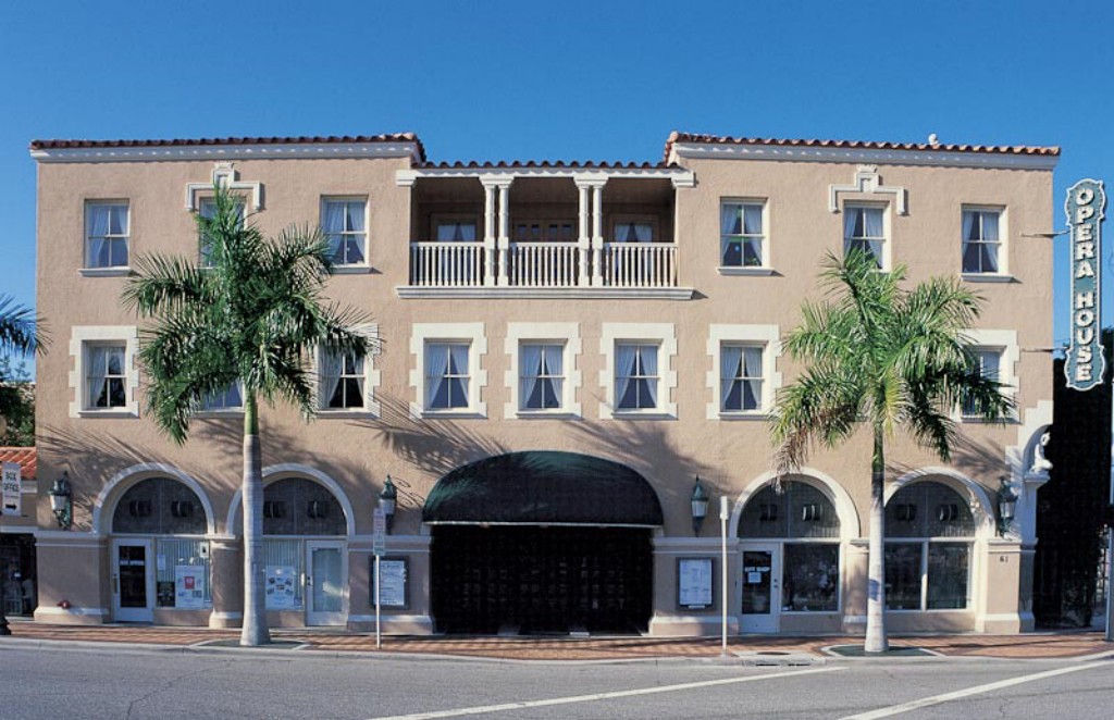 A Mediterranean-style building with palm trees and arched windows.
