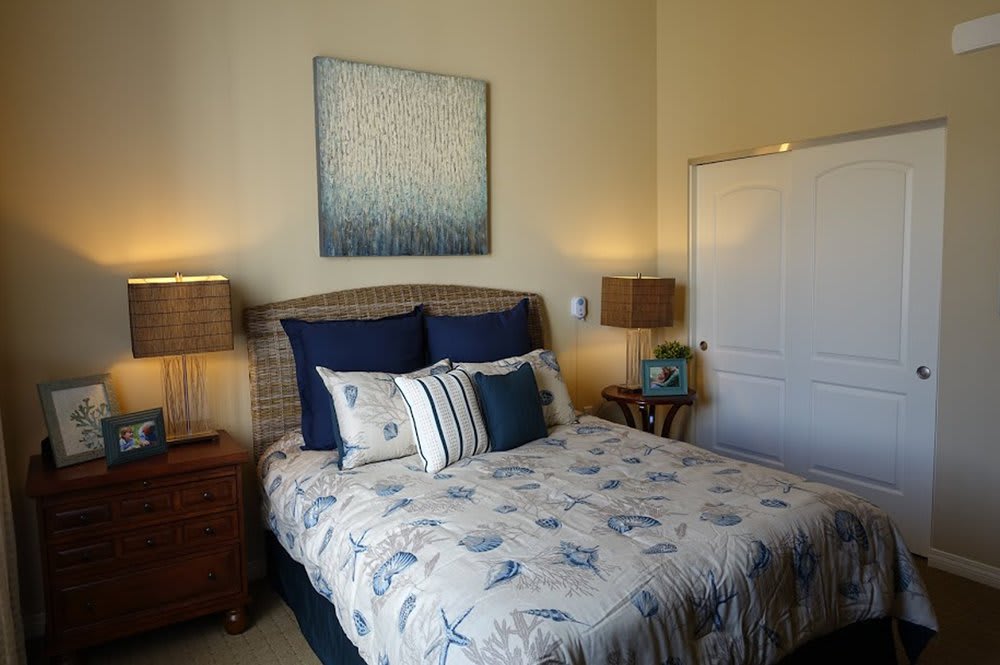 A cozy bedroom with a neatly made bed, flanked by two nightstands and lamps, featuring decorative artwork on the wall.