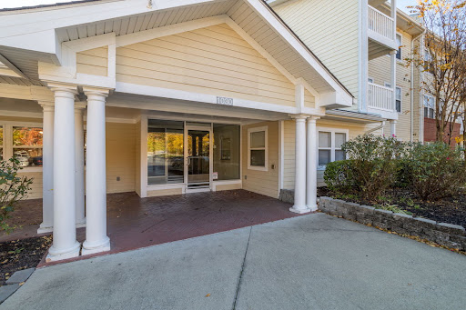 A welcoming entrance to a residential building featuring a spacious porch and glass doors.