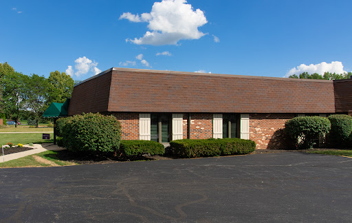 A charming brick office building surrounded by well-maintained shrubs and a clear blue sky.