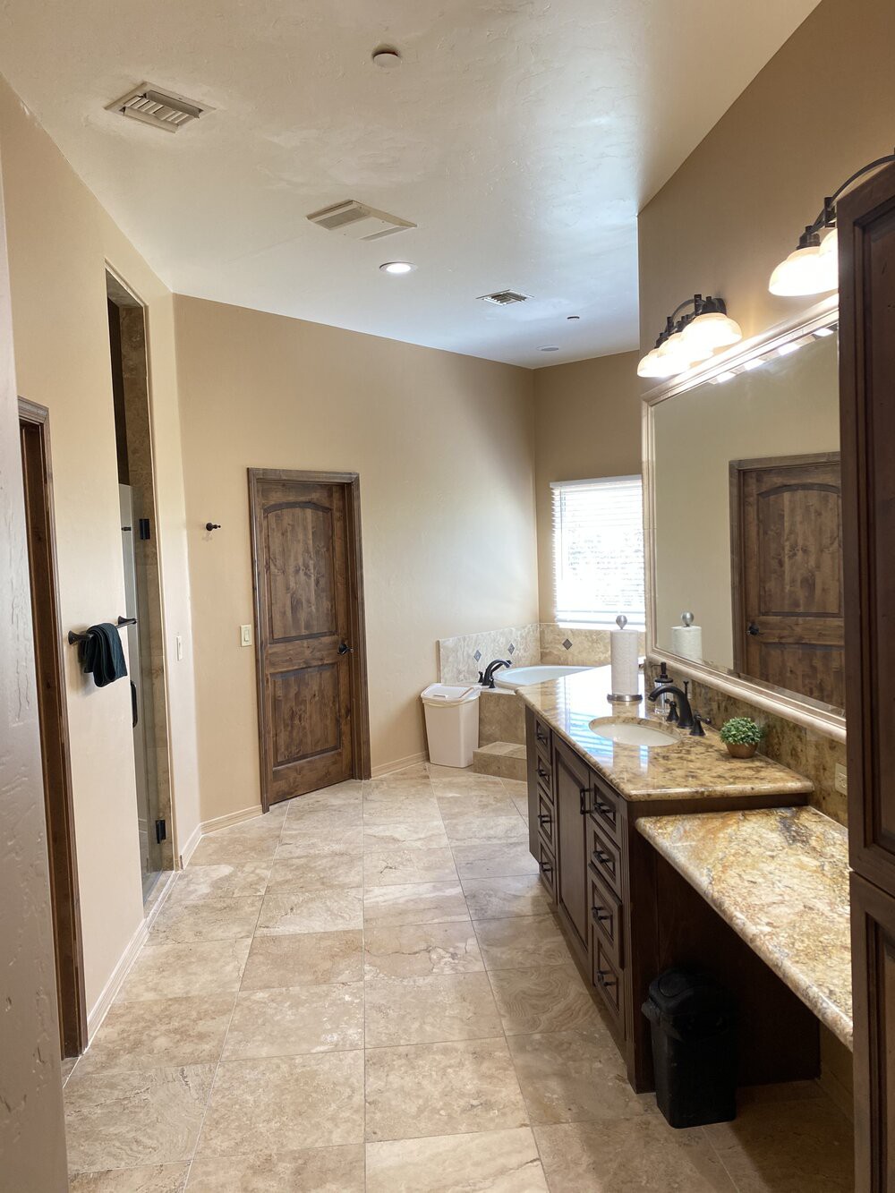 Spacious bathroom with a large mirror and elegant tile flooring.