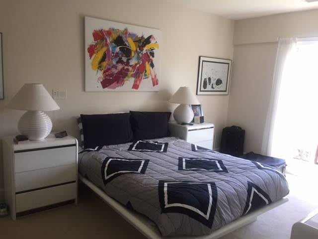 A modern bedroom with abstract art above the bed and stylish lamps on the nightstands.