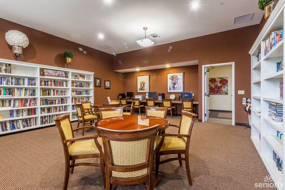 A cozy library reading area with chairs around a table and bookshelves filled with books.