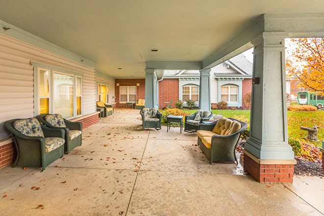 A covered patio area with outdoor seating and a pathway, adjacent to a building.