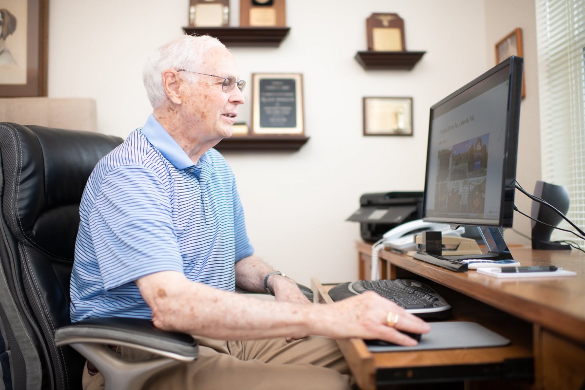 An elderly person working on a computer in an office setting.