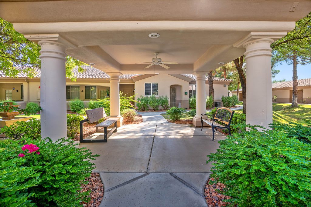 Covered entryway with benches and landscaped garden.