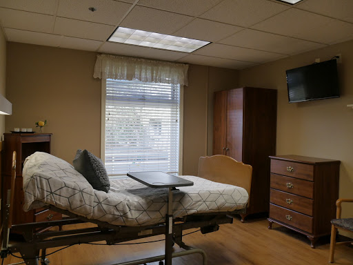 A comfortable and well-lit hospital room featuring a patient bed, window with curtains, and basic furnishings.