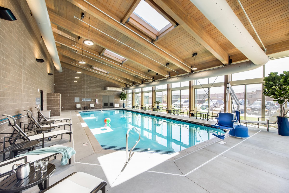 A bright indoor swimming pool with skylights and a wooden ceiling.