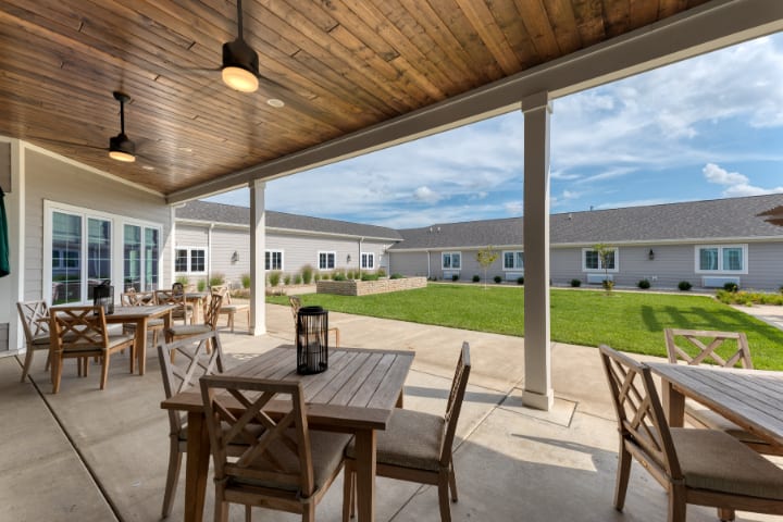 A spacious patio with wooden furniture overlooks a well-maintained garden area.