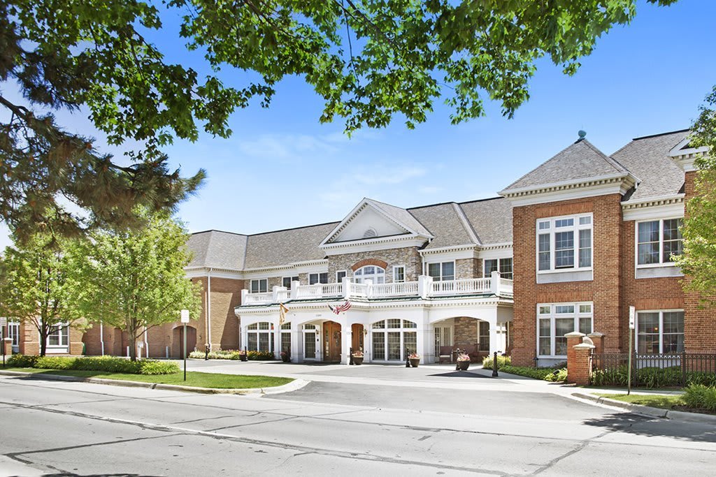 A view of a large residential building with trees and a driveway in the foreground.