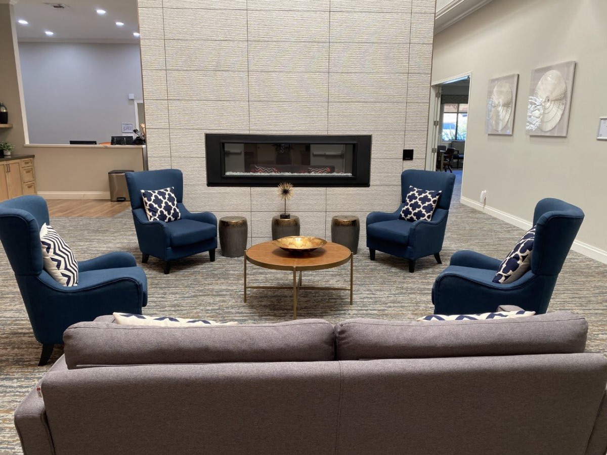 A modern living room setup with blue armchairs, a round coffee table, and a sleek fireplace.