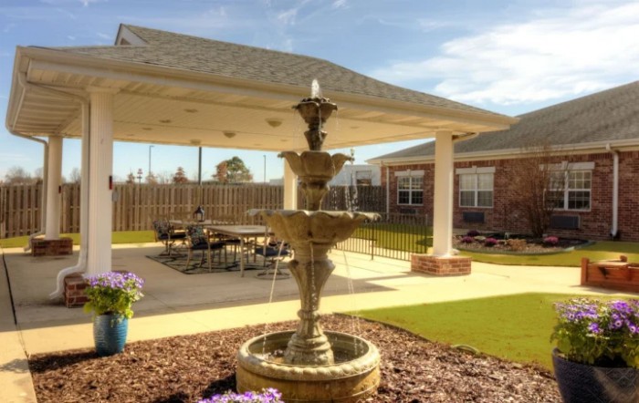 A serene outdoor patio featuring a multi-tiered fountain surrounded by a landscaped garden.