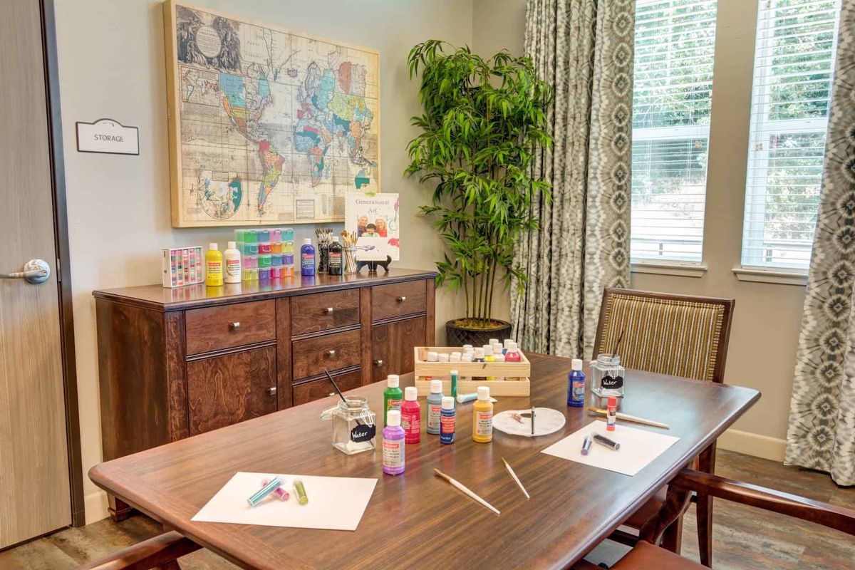 A well-organized art and craft workspace featuring a variety of paints, brushes, and canvases on a wooden table.