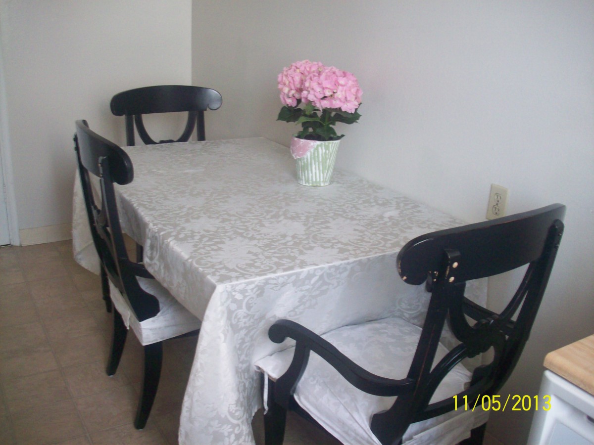A cozy dining area with a table adorned with a tablecloth and a potted plant centerpiece.
