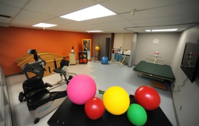 A therapy room with colorful exercise balls and rehabilitation equipment.
