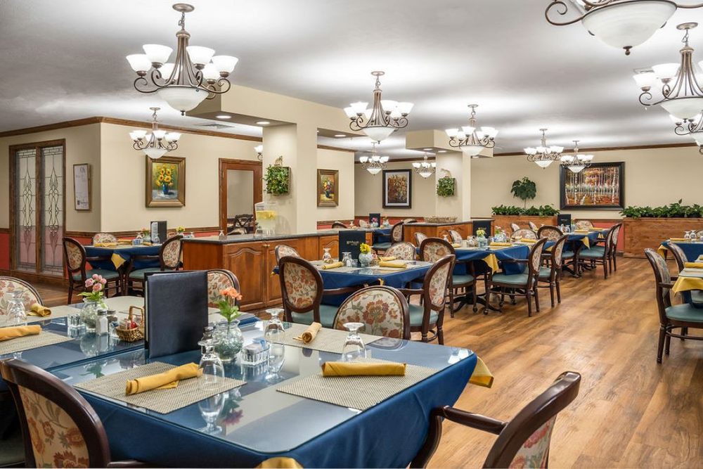 A spacious dining room with elegantly set tables and decorative chandeliers.