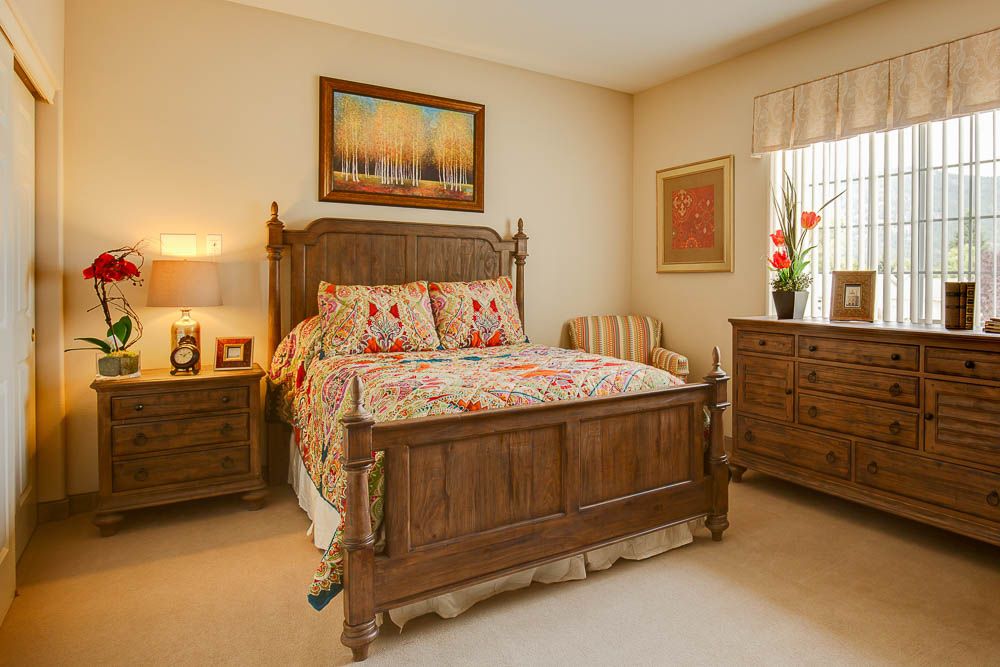 A cozy bedroom featuring a wooden bed frame, nightstands, dresser, and decorative elements.