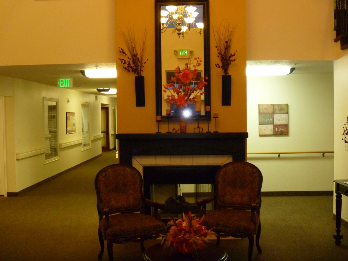 A warmly decorated lobby with a seating area featuring two chairs, a fireplace, and ornate decorations.