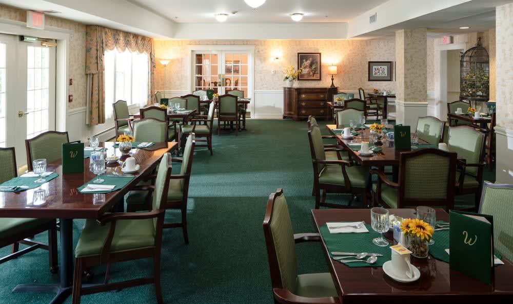 A well-lit dining area with neatly arranged tables and chairs, featuring elegant decor.