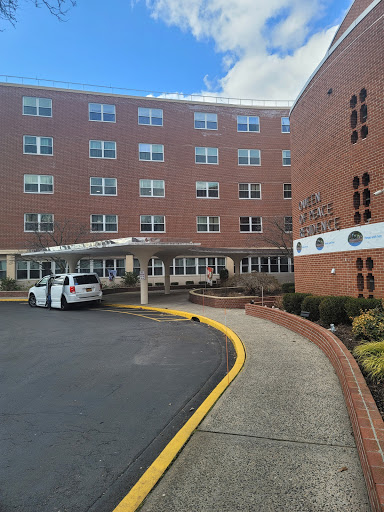 A view of a healthcare facility with a curved driveway and a parked vehicle.