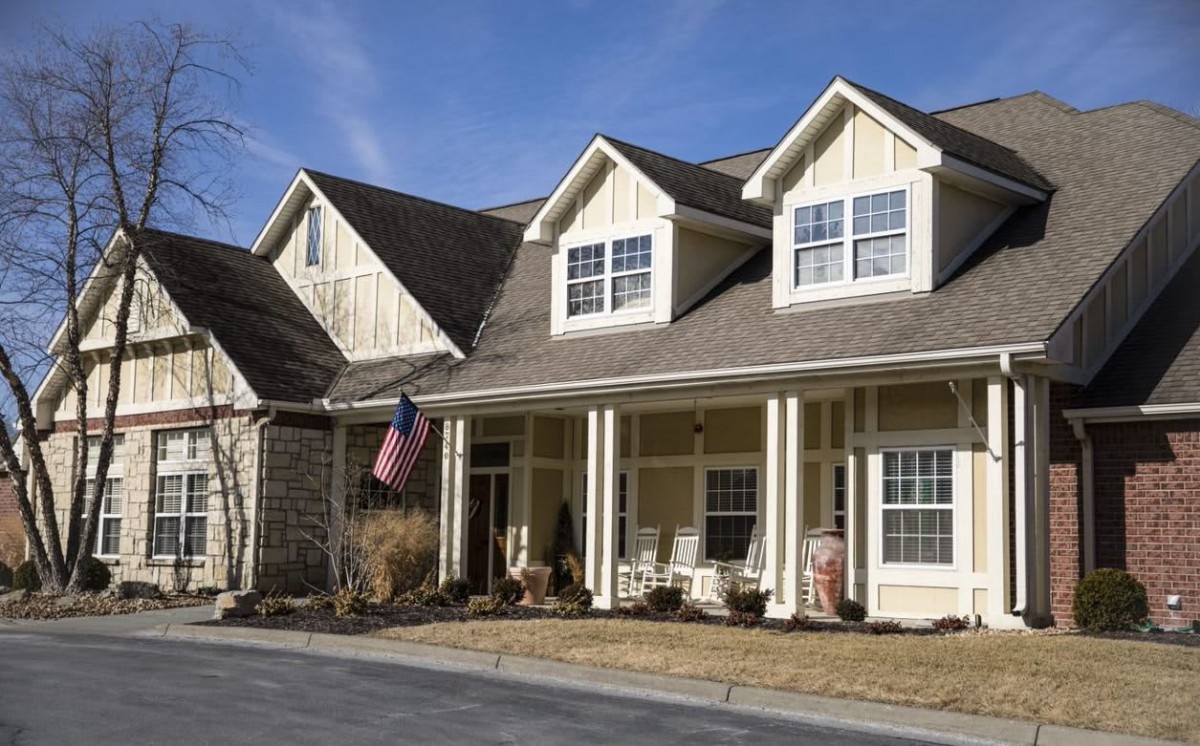 A traditional suburban house with a porch and an American flag.