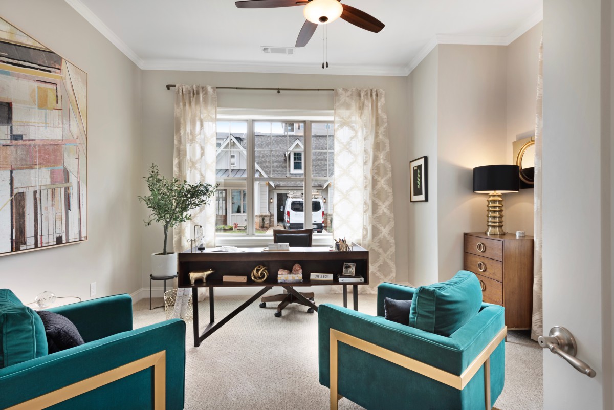 A modern home office with a large window, featuring stylish furniture and decor.