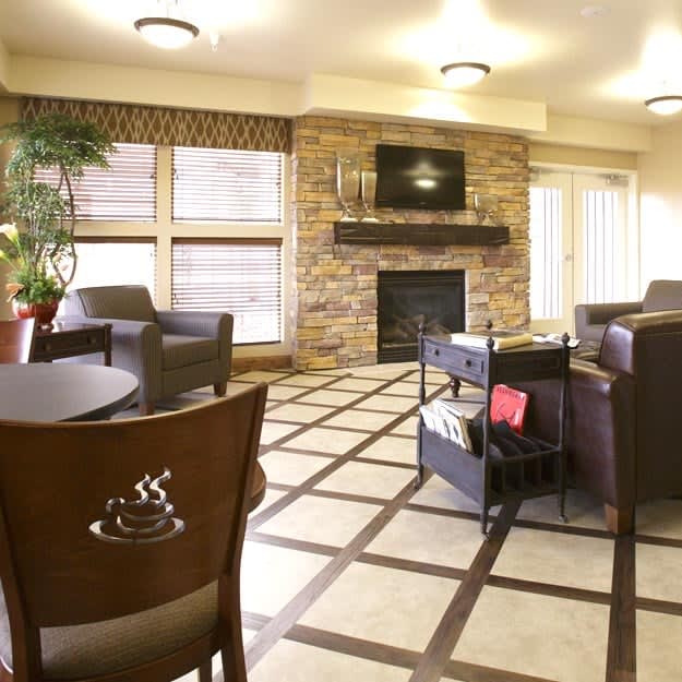 A cozy living room with modern furniture, a stone fireplace, and a wall-mounted television.