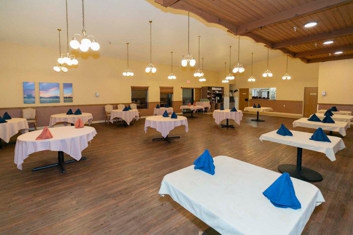 A spacious and elegantly decorated restaurant dining room with neatly arranged tables and chandeliers.